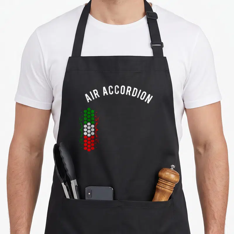 Edition mexico apron - White AIR ACCORDION text arching over green white and red button column with swirls — shown on a black cotton canvas apron against a white background