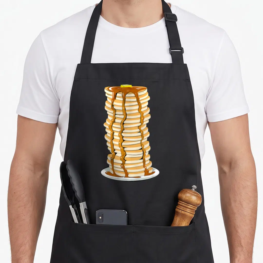 Stack pancake apron - Cartoon illustration of a tall stack of pancakes with butter and syrup on a white plate — shown on a black cotton canvas apron against a white background