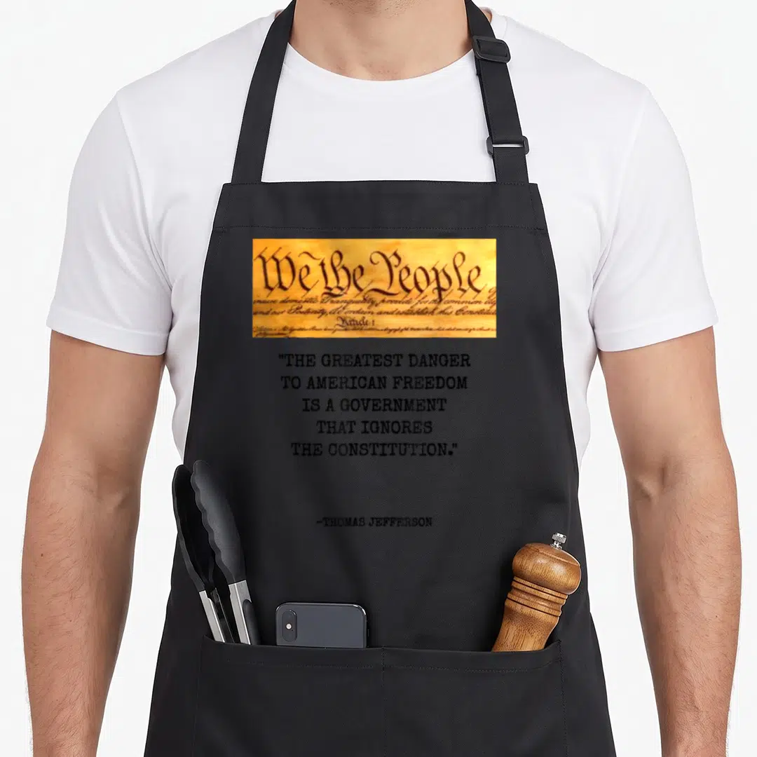 Greatest star quotes apron - We the People parchment strip above stacked Thomas Jefferson quote about government — shown on a black cotton canvas apron against a white background