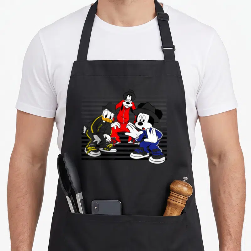Donald street apron - Three cartoon characters in red blue and black street wear standing against grey and black stripes — shown on a black cotton canvas apron against a white background