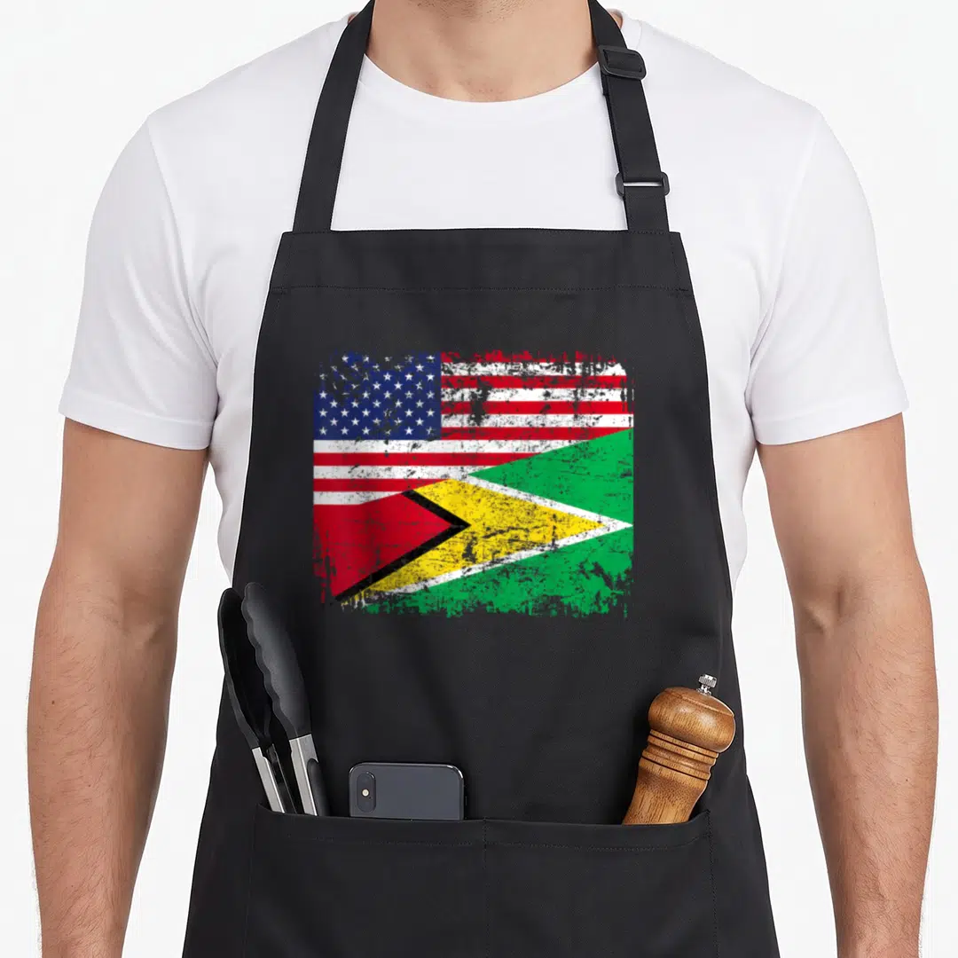 Guyanese american flag apron - Distressed merged US and Guyana flag print in red white blue green and yellow — shown on a black cotton canvas apron against a white background