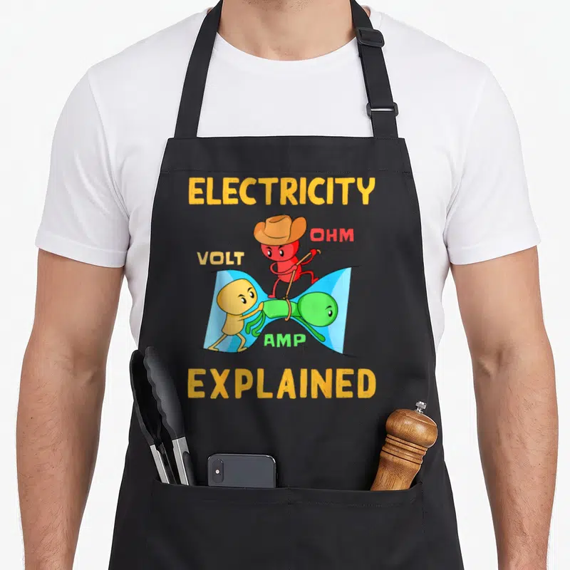Volt electrician apron - ELECTRICITY EXPLAINED text above red Ohm on green Amp pulled by yellow Volt with blue — shown on a black cotton canvas apron against a white background