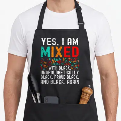 Mixed african american aprons - Stacked text YES I AM MIXED WITH BLACK abstract shapes teal orange red distressed font — shown on a black cotton canvas apron against a white background