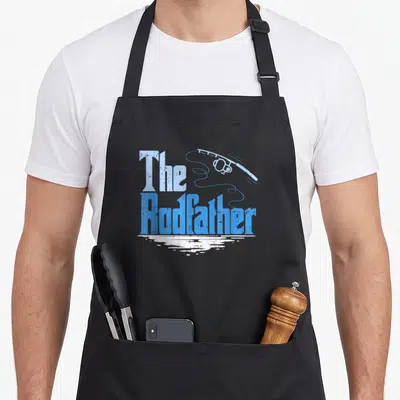 Rodfather fishing apron - Distressed blue text The Rodfather with fishing rod and white water reflection — shown on a black cotton canvas apron against a white background