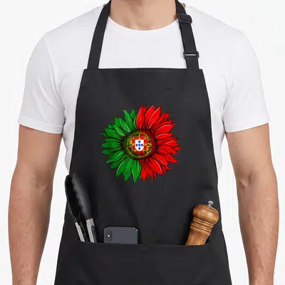 Sunflower portuguese apron - Cartoon sunflower with green left petals, red right petals, and Portuguese coat of arms — shown on a black cotton canvas apron against a white background