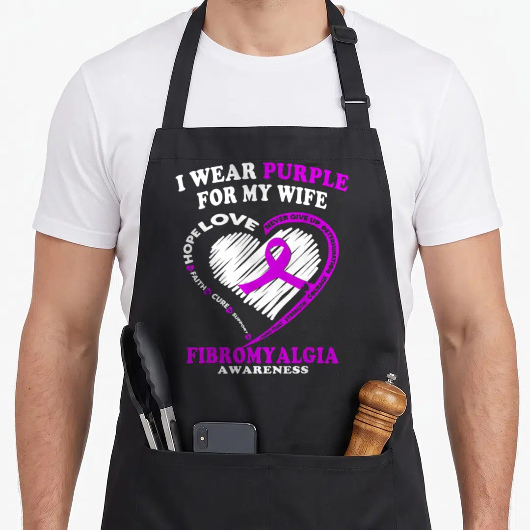 Fibromyalgia wife apron - I WEAR PURPLE FOR MY WIFE text around white heart with purple ribbon — shown on a black cotton canvas apron against a white background