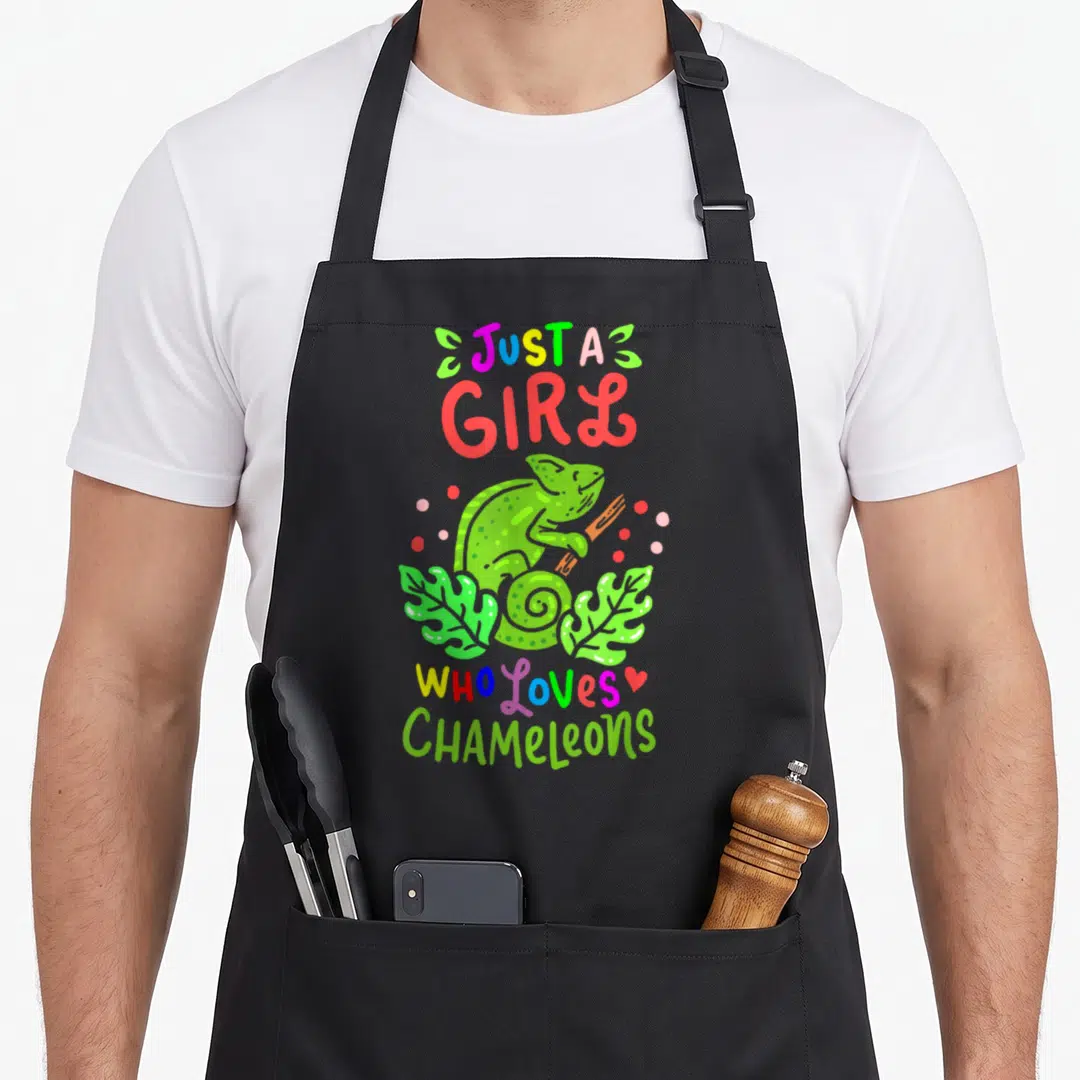 Raptile chameleon apron - Cartoon green chameleon on branch with text Just a Girl Who loves CHAMELEONS and colorful dots — shown on a black cotton canvas apron against a white background