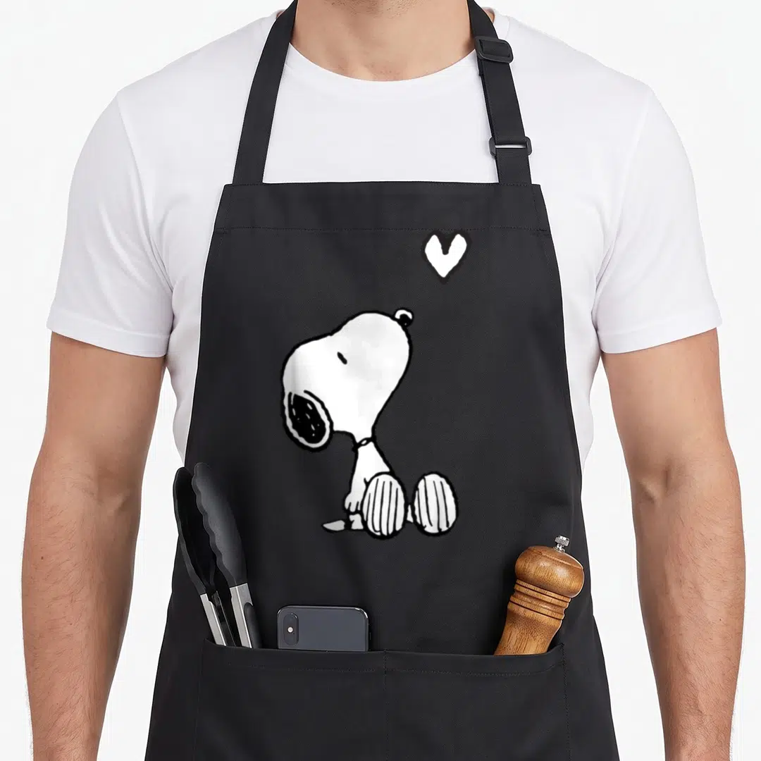 Funny sitting valentine apron - Snoopy sitting profile with a floating heart outline above his head — shown on a black cotton canvas apron against a white background