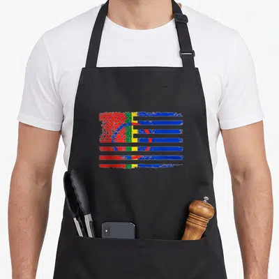 Sami american flag apron - Distressed flag with red blue green yellow white stripes, stars, and central circle — shown on a black cotton canvas apron against a white background