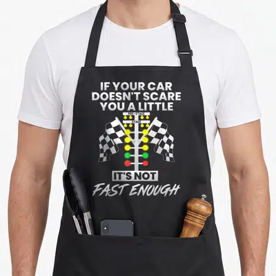 Scare car apron - Drag racing light tree with checkered flags and text about car speed — shown on a black cotton canvas apron against a white background