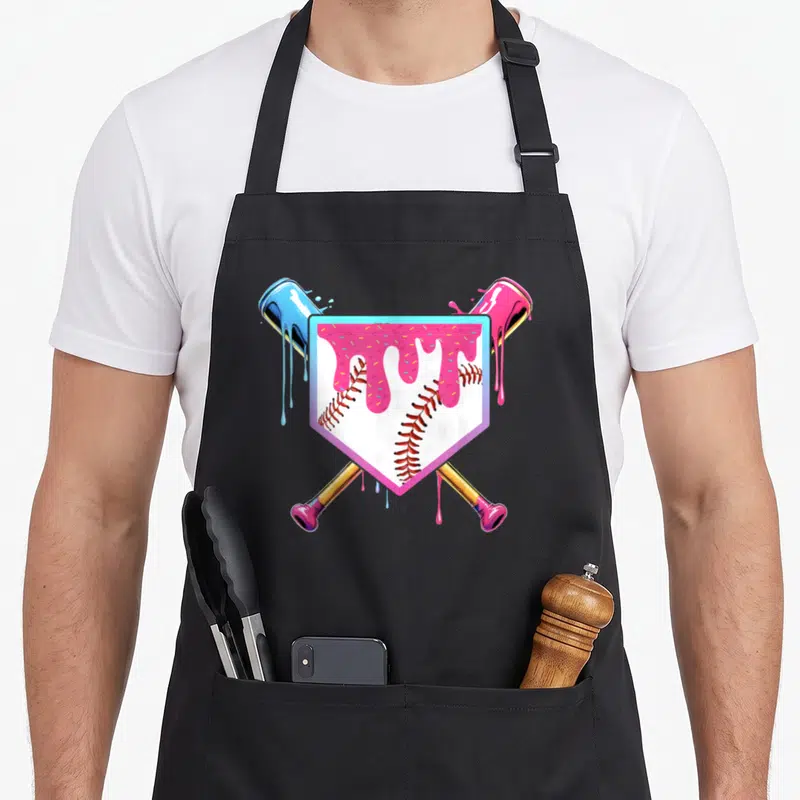 Ice drip apron - Cartoon baseball in shield with pink drip and crossed paint cans in blue and pink — shown on a black cotton canvas apron against a white background