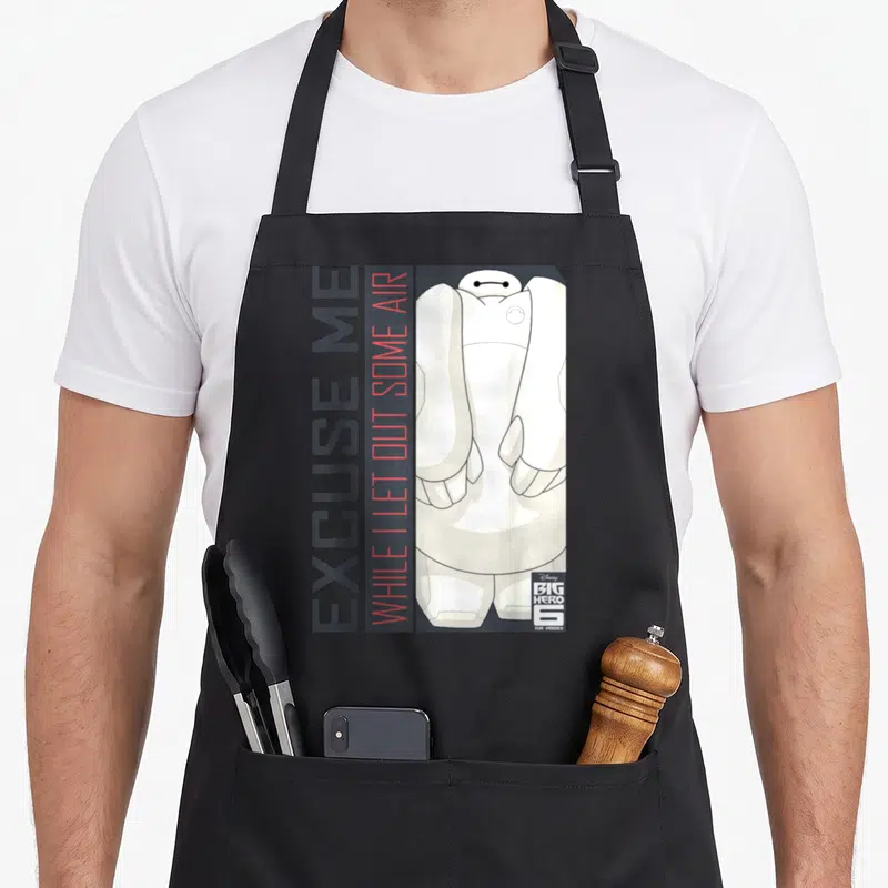 Baymax thriller apron - Vertical text EXCUSE ME WHILE I LET OUT SOME AIR beside white Baymax cartoon figure — shown on a black cotton canvas apron against a white background