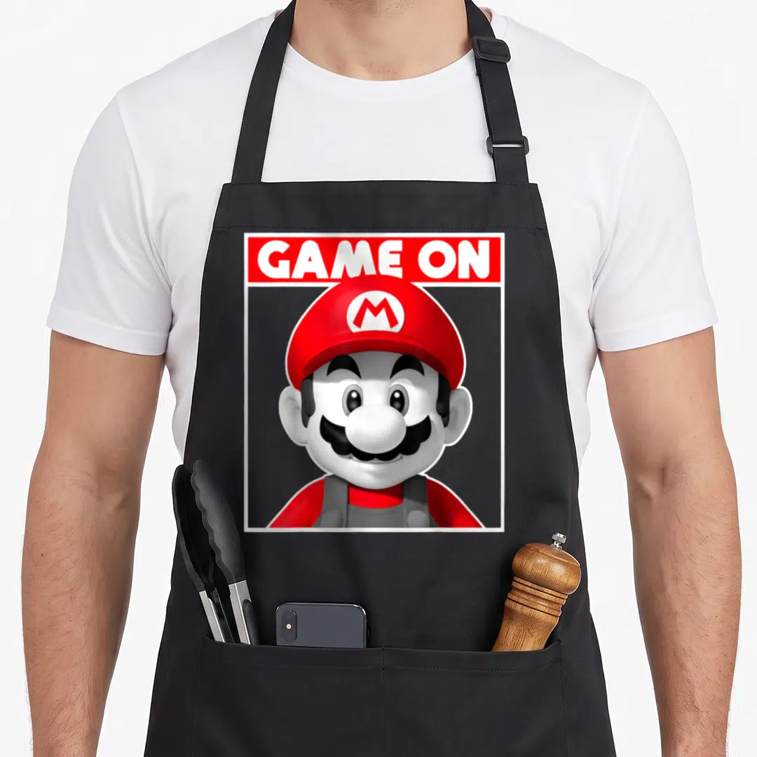 Box game aprons - Mario head and shoulders below GAME ON text in red rectangle with white border — shown on a black cotton canvas apron against a white background