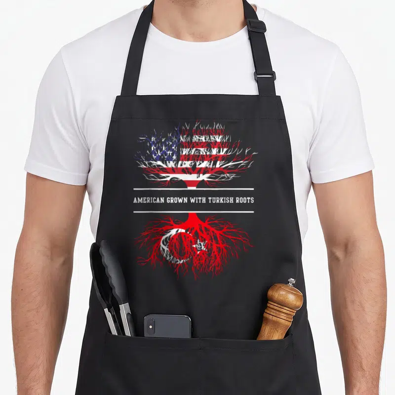 Grown turkey apron - Tree filled with US and Turkey flags separated by two white lines and text — shown on a black cotton canvas apron against a white background