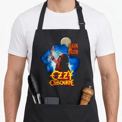 Bark ozzy osbourne apron - Werewolf over blue splash with Bark At The Moon and Ozzy Osbourne text — shown on a black cotton canvas apron against a white background