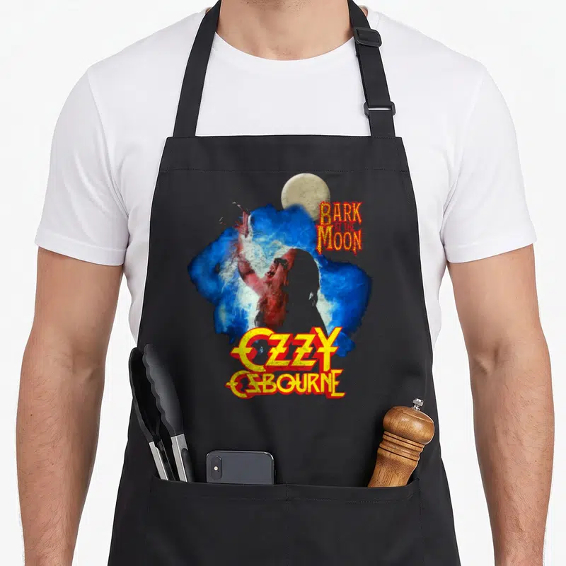 Bark ozzy osbourne apron - Werewolf over blue splash with Bark At The Moon and Ozzy Osbourne text — shown on a black cotton canvas apron against a white background
