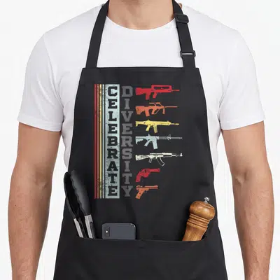 Different gun apron - Vertical CELEBRATE DIVERSITY text beside seven stacked colored gun silhouettes with distressed — shown on a black cotton canvas apron against a white background
