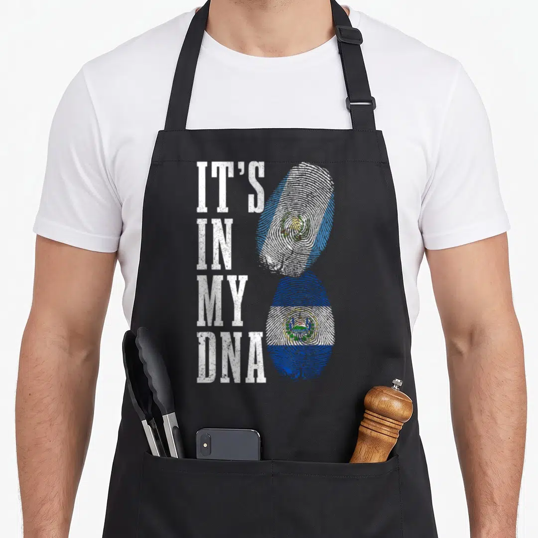 Salvador guatemalan aprons - IT'S IN MY DNA text next to stacked fingerprint flags in Guatemalan and Salvadorian colors — shown on a black cotton canvas apron against a white background