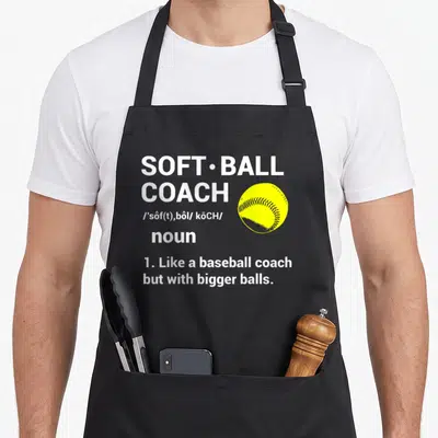 Ball coach baseball apron - Dictionary style text reading SOFT•BALL COACH next to a yellow softball illustration — shown on a black cotton canvas apron against a white background