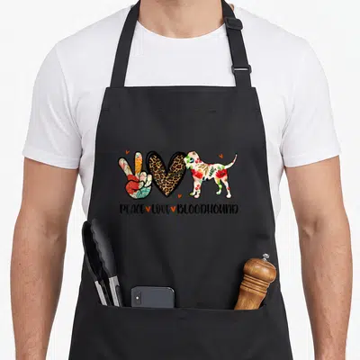 Peace bloodhound dog apron - Cartoon peace sign, leopard heart, and floral bloodhound with text PEACE LOVE BLOODHOUND — shown on a black cotton canvas apron against a white background