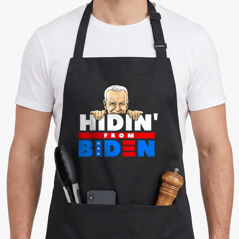 Hiding political aprons - Cartoon of Joe Biden peeking over white HIDIN text above red bar and flag-patterned BIDEN — shown on a black cotton canvas apron against a white background