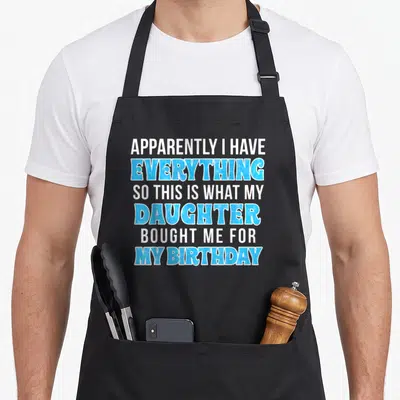Retro birthday apron for the kitchen - Stacked white and blue text reading apparently i have everything so this is what — shown on a black cotton canvas apron against a white background