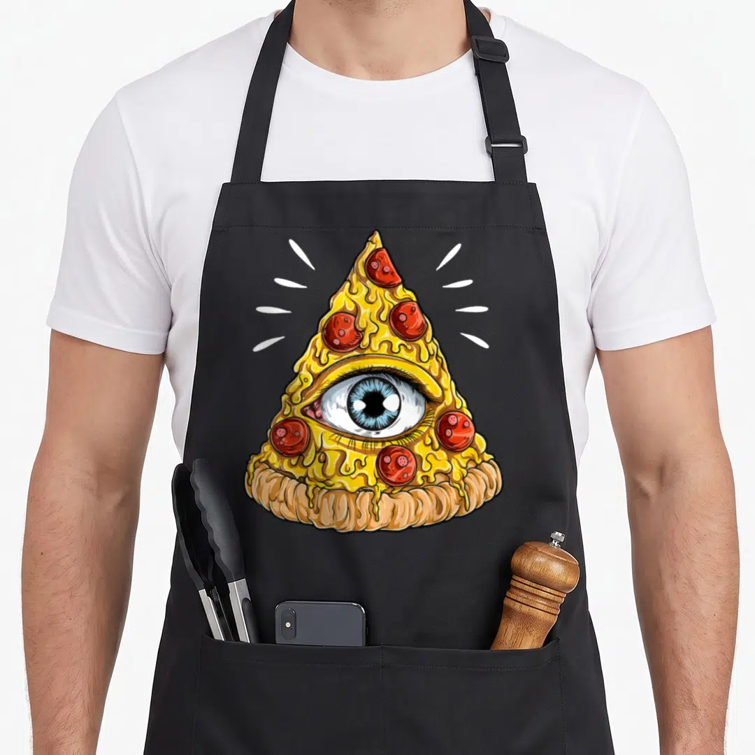 Shane pizza apron - Cartoon pepperoni pizza slice with blue human eye in cheese and white radiating lines — shown on a black cotton canvas apron against a white background