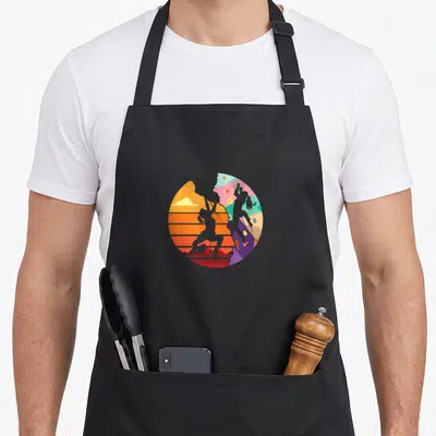 Sport bouldering apron - Circular split design of grey rock climber silhouettes against orange sunset and colorful — shown on a black cotton canvas apron against a white background