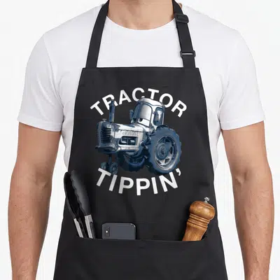 Tractor car apron - Cartoon tractor in blue silver and white with arched text reading Tractor Tippin — shown on a black cotton canvas apron against a white background
