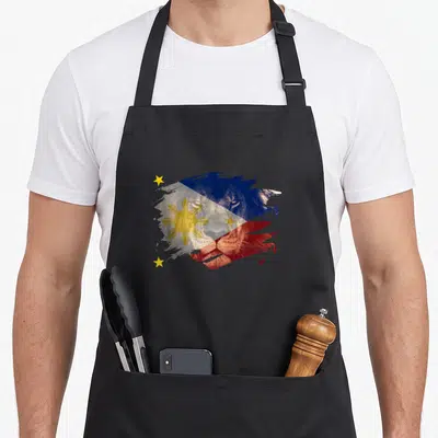 Philippine african apron - Lion head shape filled with blue red yellow white Philippine flag splatter art — shown on a black cotton canvas apron against a white background