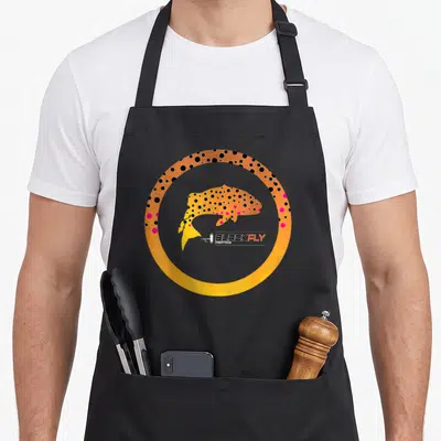 Skin fishing aprons - Orange spotted fish inside a thick circular border with pink and black dots — shown on a black cotton canvas apron against a white background