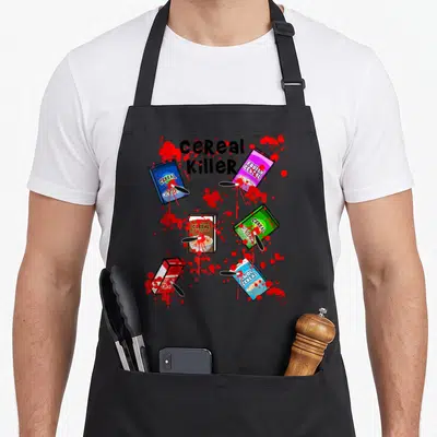 Cereal halloween apron - Cereal Killer text with five stabbed cereal boxes and red blood splatter art — shown on a black cotton canvas apron against a white background