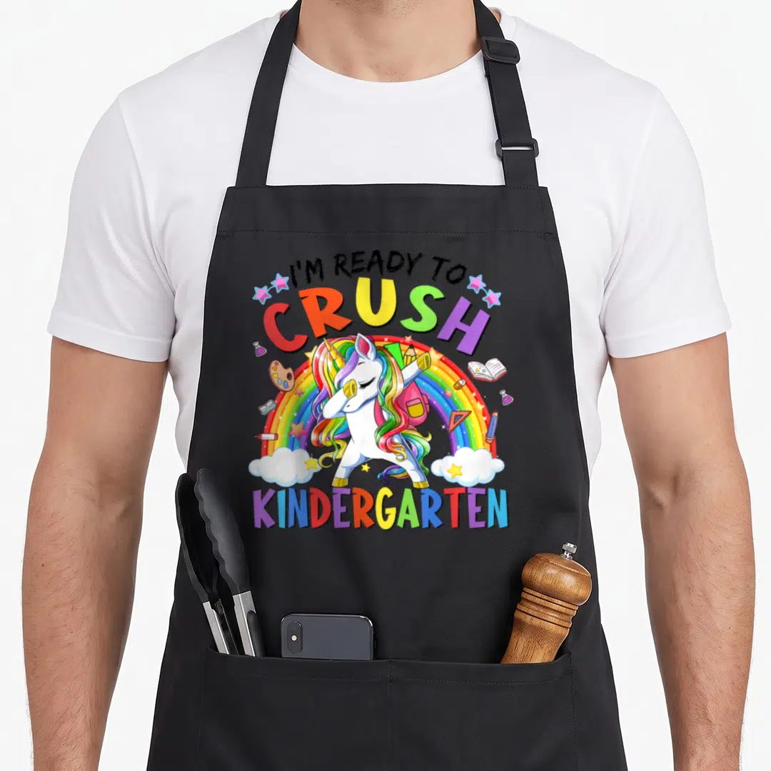 Crush kindergarten teacher apron - Dabbing unicorn over rainbow with school supplies and text I'm ready to crush — shown on a black cotton canvas apron against a white background