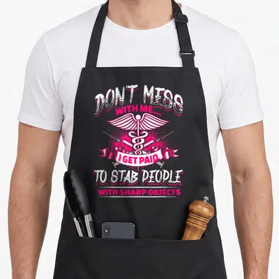 Stab nursing apron - Pink and white caduceus with crossed scalpels and stab people quote — shown on a black cotton canvas apron against a white background