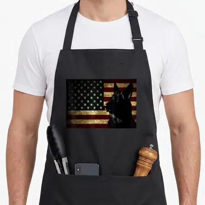 Flag dog mom apron - Black German Shepherd profile over distressed red gold blue USA flag — shown on a black cotton canvas apron against a white background