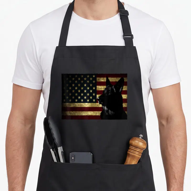 Flag dog mom apron - Black German Shepherd profile over distressed red gold blue USA flag — shown on a black cotton canvas apron against a white background