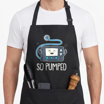 Pumped diabete awareness apron - Cartoon insulin pump character giving thumbs up with text SO PUMPED below — shown on a black cotton canvas apron against a white background