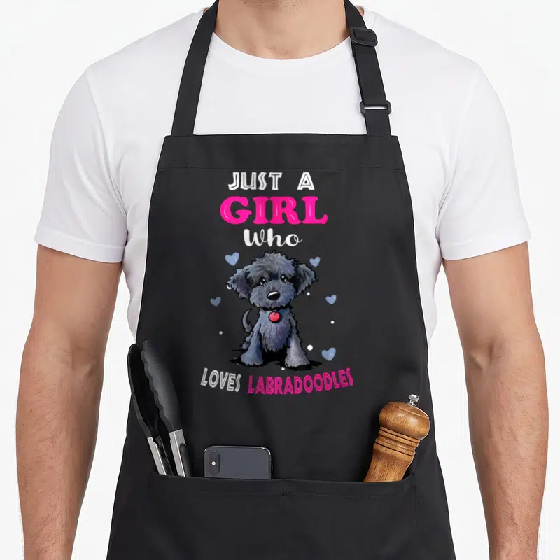 Vintage labradoodle dog apron - Cartoon grey labradoodle with pink text and blue hearts on grey background — shown on a black cotton canvas apron against a white background