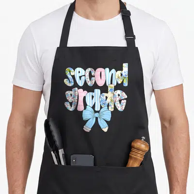 Second bow apron - Stacked second grade text in floral and gingham patterns with a blue striped pencil bow — shown on a black cotton canvas apron against a white background