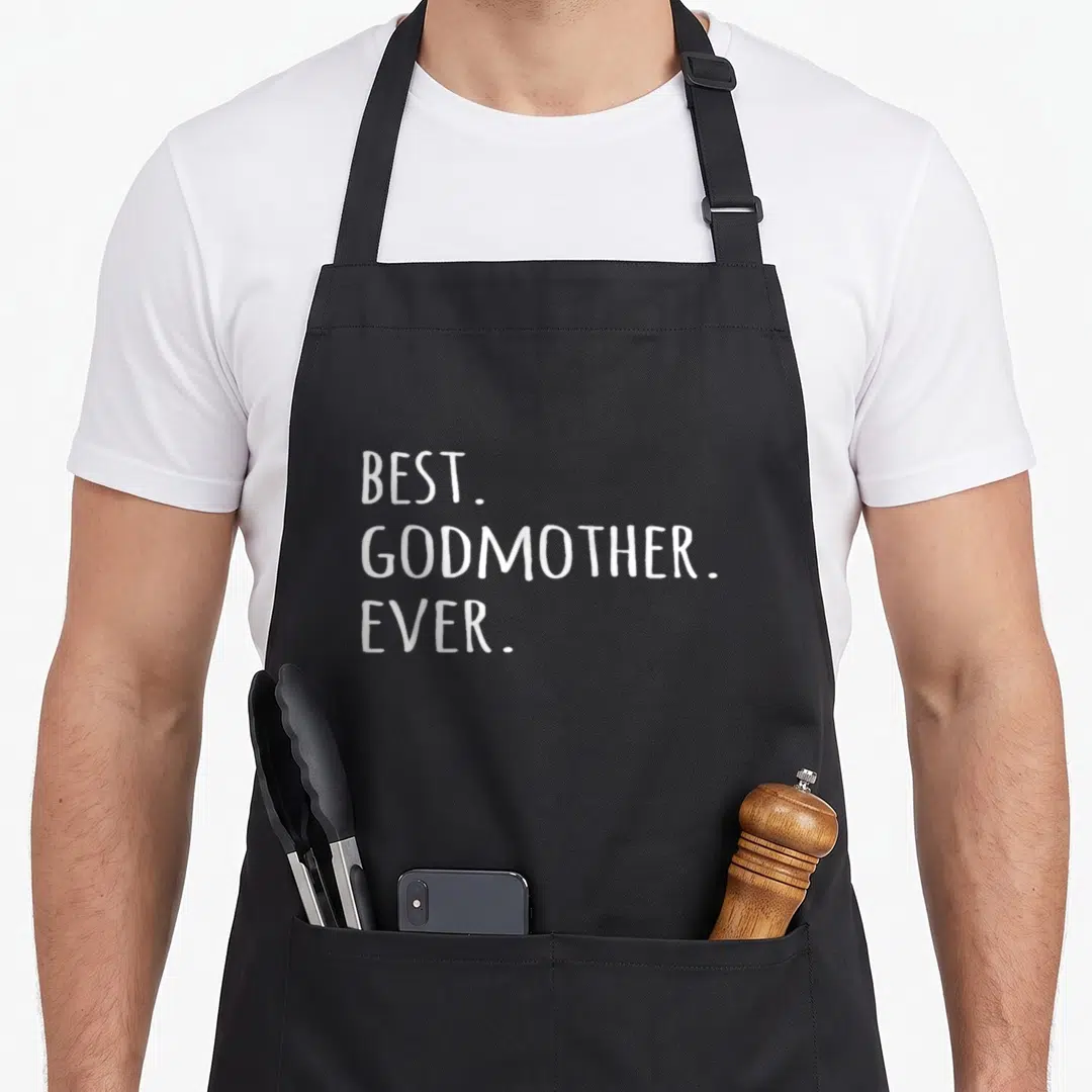 Godmother mother's apron - White stacked text reading BEST GODMOTHER EVER on grey background — shown on a black cotton canvas apron against a white background