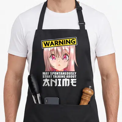 Clothe anime apron - Pink anime girl face under yellow WARNING sign with white stacked text — shown on a black cotton canvas apron against a white background