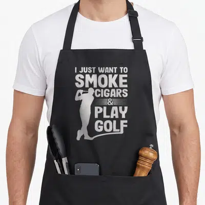 Smoke golf apron - Distressed white I Just Want to Smoke Cigars & Play Golf text with golfer silhouette — shown on a black cotton canvas apron against a white background