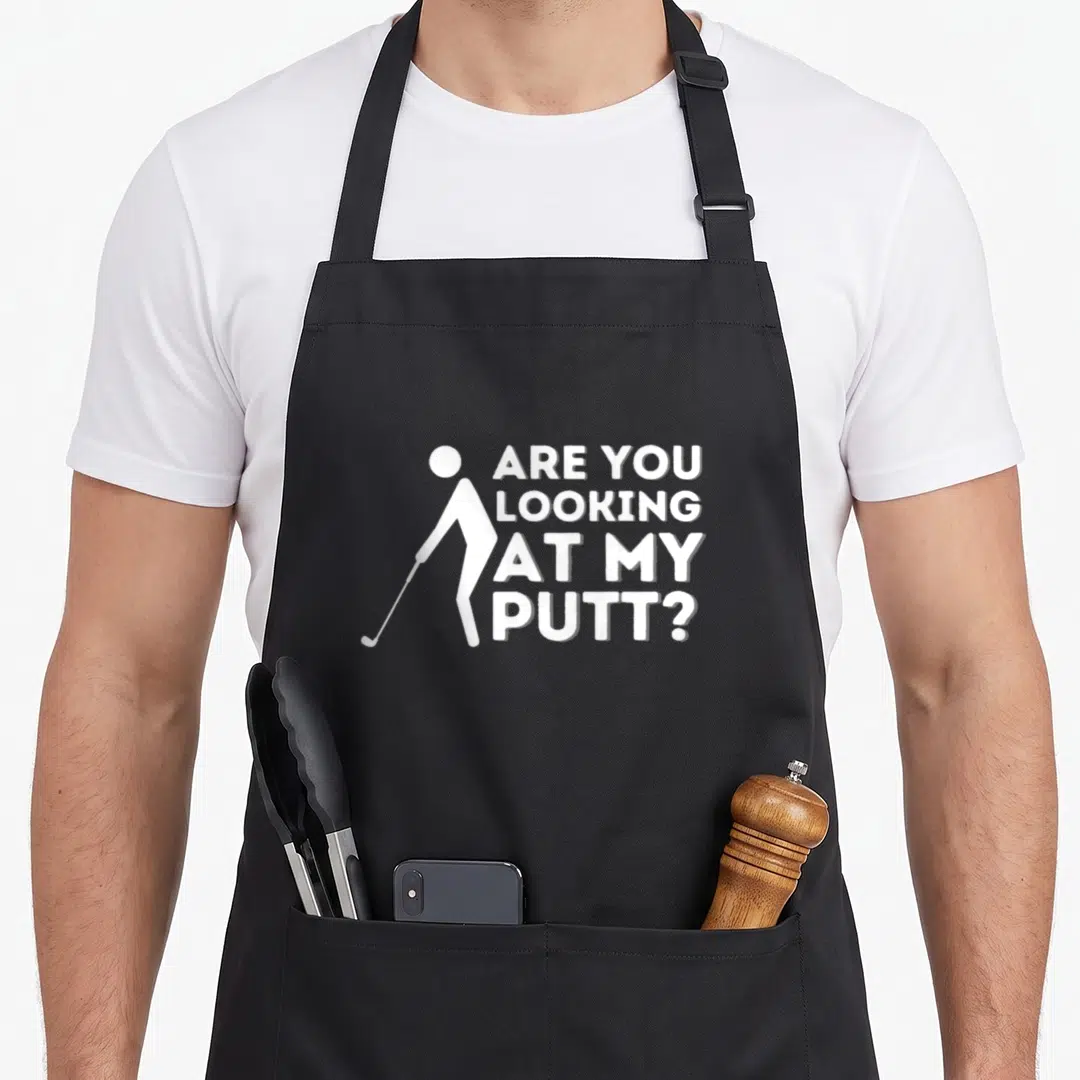 Putt golf apron - White stick golfer holding club next to stacked text Are You Looking At My Putt — shown on a black cotton canvas apron against a white background
