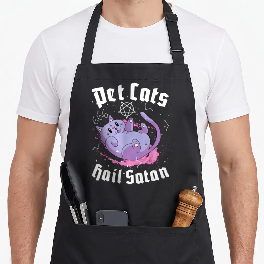 Pet cat apron - Purple cartoon cat lying on pink splash with Pet Cats Hail Satan text and pentagram — shown on a black cotton canvas apron against a white background
