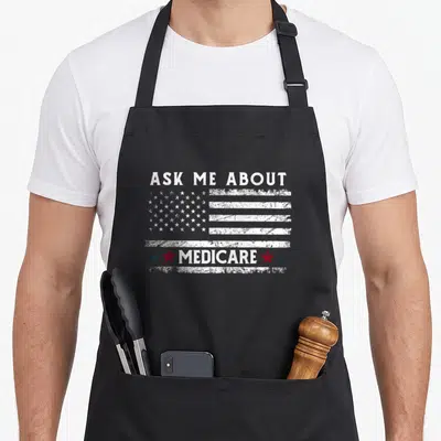Ask health insurance agent healthcare medicare apron - Distressed USA flag with ASK ME ABOUT MEDICARE text and four — shown on a black cotton canvas apron against a white background