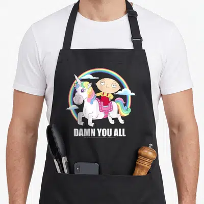 Chest iconic aprons - Stewie Griffin riding white unicorn rainbow arc DAMN YOU ALL text cartoon style — shown on a black cotton canvas apron against a white background