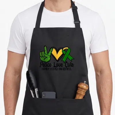 March ribbon apron - Green peace sign hand, yellow heart, green ribbon, and text Peace Love Cure Kidney Disease — shown on a black cotton canvas apron against a white background