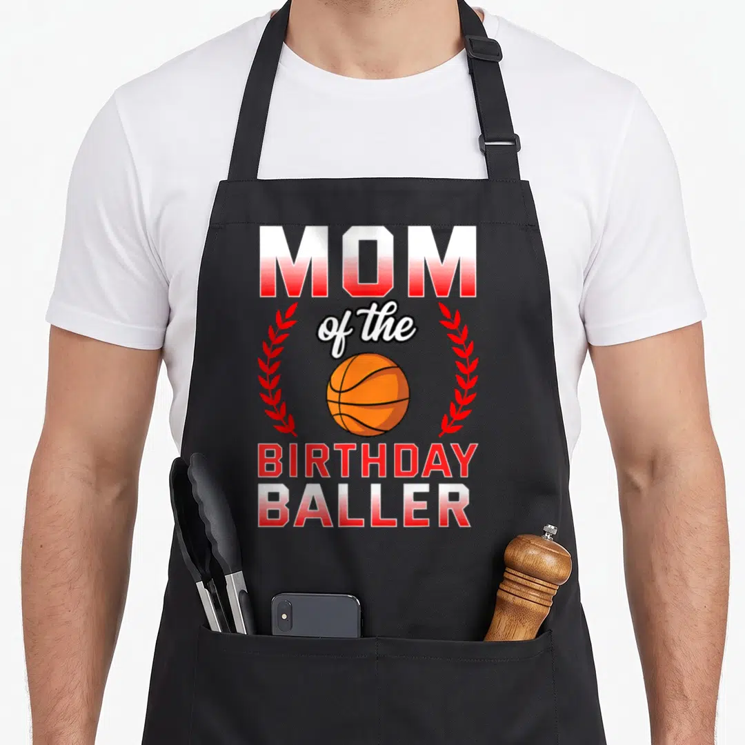 Basketball bday birthday apron - MOM of the BIRTHDAY BALLER text with orange basketball and red laurel branches — shown on a black cotton canvas apron against a white background