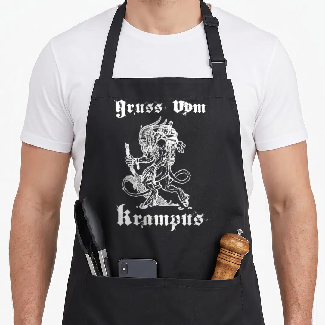 Gruss vom christmas apron - White Krampus line art holding sticks and basket with Gruss Vom text — shown on a black cotton canvas apron against a white background