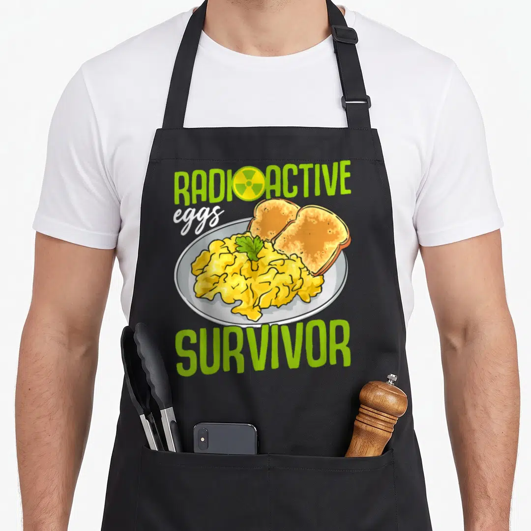 Gastroparesis egg apron - Cartoon plate of scrambled eggs and toast with Radioactive Eggs Survivor text and radiation — shown on a black cotton canvas apron against a white background